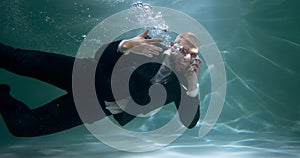 Anger management concept. Young stressed boss businessman swimming underwater, shouting during phone call slow motion.