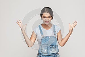 Anger spanish woman in despair and shock. Portrait of young adult angry woman in blue denimoveralls, looking panic in camera wit