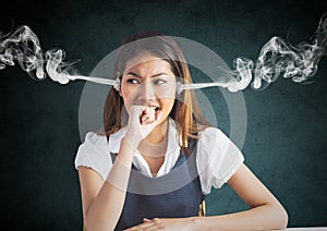 anger young woman with steam on ears and hand on the mouth. Black and grey background
