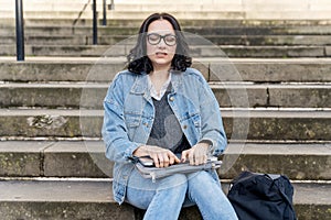 angered woman student e learning distance training course working on stairs in city. young woman watching online education