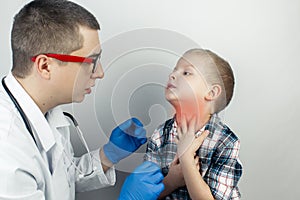 A pediatrician examines a boy who complains of a sore throat. Diagnosis of tracheal diseases. Angina, tonsillitis, pharyngitis, photo