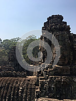 Angkor Wat in Siem Reap, Cambodia. Stone faces carved in the ancient ruins of Bayon Khmer Temple