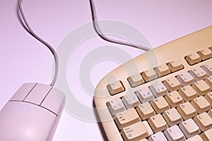 Angle top view of an old computer keyboard and a mouse with their wires on a white background