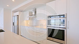 Angle view on contemporary kitchen design in cozy penthouse with new built-in appliances from stainless steel. Bright