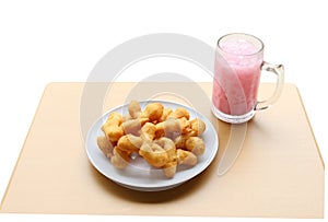 Angle view of deep-fried dough stick with pink cold drink on woo