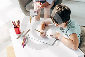 Angle view of kid with dyslexia drawing on paper with pencil