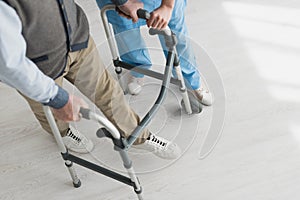 Angle view of retired man walking with doctor, recovering after injury