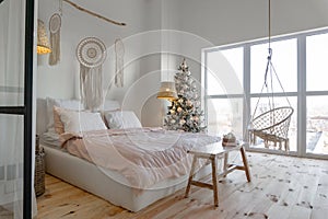 Angle view on spacious white bedroom with big windows decorated with Christmas New year tree and tea set