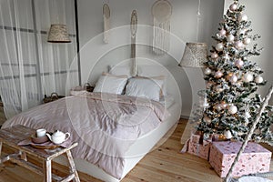 Angle view on spacious white bedroom decorated with Christmas New year tree and tea set