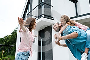 Angle view of woman with outstretched hands near man piggybacking daughter