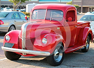 Angled front view of a 1940's model red Ford 3100 pick-up truck.