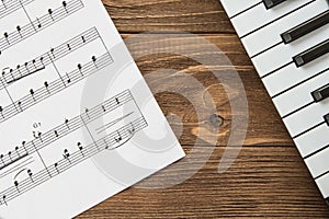 Angled piano keyboard on wooden background with notes