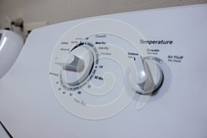 Angled, selective focus on the knob control panel of a white clothes dryer