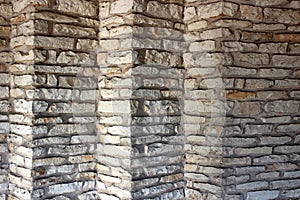 Angled stone wall of building, with rough texture and pretty patterns throughout
