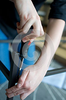 Angled veritcal close up of hands screwing together metal furniture pieces photo