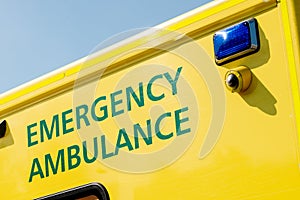 Angled view of EMERGENCY AMBULANCE sign on yellow NHS vehicle. photo