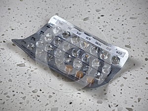 Angled view of an almost empty blister pack of birth control pills on a white counter top