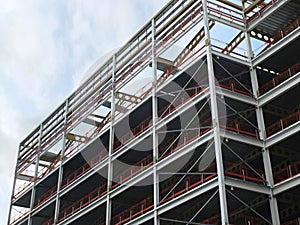 Angled view of a large building development under construction with steel framework and girders supporting the metal floors with b