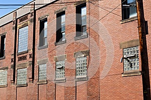 Angled view of old red brick industrial building, lower windows filled with glass block, interesting architectural details