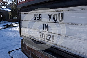 Angled view of a school changeable letter sign on a snowy day that says See You in 2022