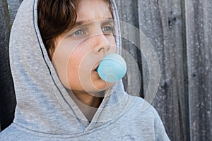 Angled view of teenage boy blowing blue bubble gum