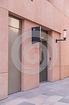 Angled View of Terracotta Wall with Metal and Glass Doors: Navigational Sign and Street Light Included