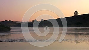 Angler catches fish at dawn in the fog