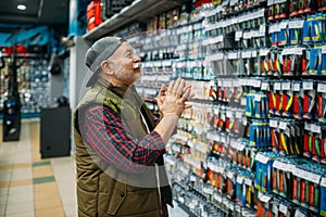 Angler choosing hooks and baubles in fishing shop