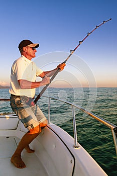 Angler fisherman fighting big fish from the boat photo