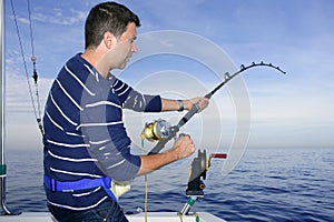 Angler fisherman fighting big fish rod and reel photo