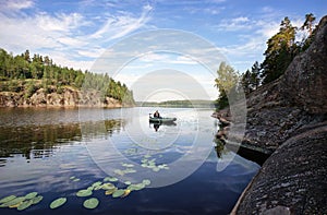 Angler fishing on boat in  nordic rocky bay. North Europe, Baltic sea, gulf of Finland