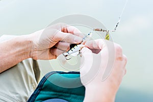 Angler fixing lure at hoof of fishing rod