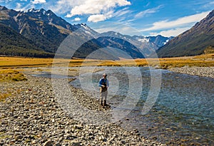 An Angler fly fishing for trout on the Ahuriri river, surrounded by mountains