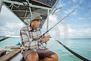 angler holding a fishing rod and checking the reel