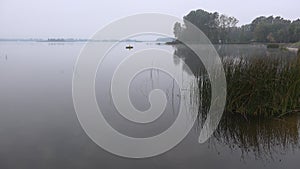 Angler man row sitting in wooden boat rowboat on lake cover with dense fog. 4K