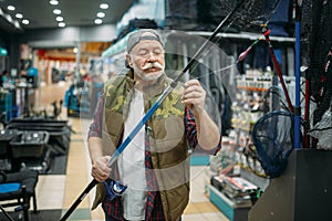 Angler puts line in the eye of rod, fishing shop