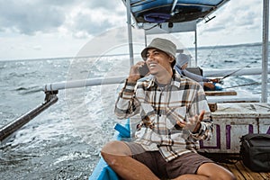 angler receives call sitting on a fishing boat at sea