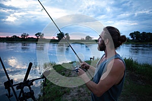 Angler on a river bank at twilight