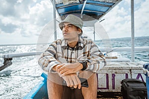 angler sits holding a cell phone on a fishing boat