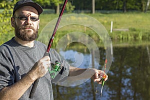 Angler stands over the water and shows a set for catching live fish.