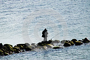 Angler on stones sillhouette