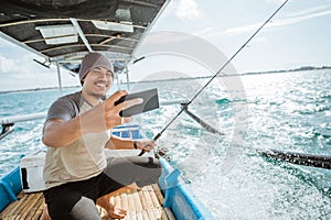 angler takes a cell phone selfie while fishing with boat