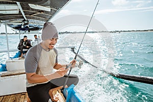 angler using cell phone while fishing with small fishing boat