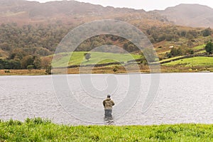 Angler in waders waiting for a catch at Watendlath