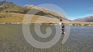 An angler wading and fly fishing for trout in the Ahuriri River, New Zealand