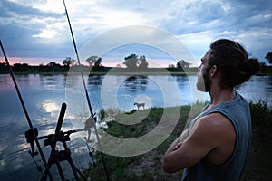 Angler waiting on a river bank at twilight
