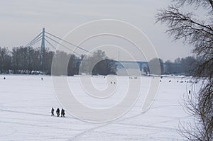 Anglers with equipment are fishing on the river Dnipro on ice in winter day. Fishermen. Kyiv, Ukraine