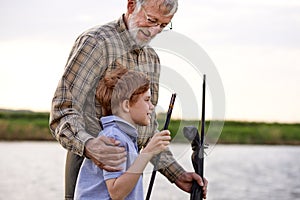 Anglers. Family bonding. Boy with grandfather fishing outdoor over river background