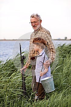 Anglers. Family bonding. Boy with grandfather fishing outdoor over river background