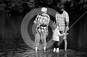 Anglers. Fly fishing for trout. Father teaching son how to fly-fish in river. Grandfather and father with cute child boy